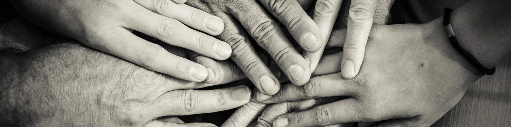 Black and white image of people's hands holding each other